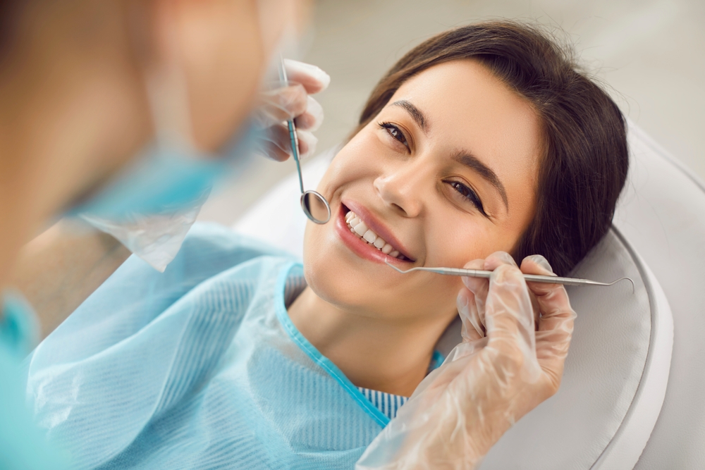 Woman smiling in dental chair during check-up, dentist using tools for oral examination, emphasizing comfort and care at Larson Dental in Prescott Valley.